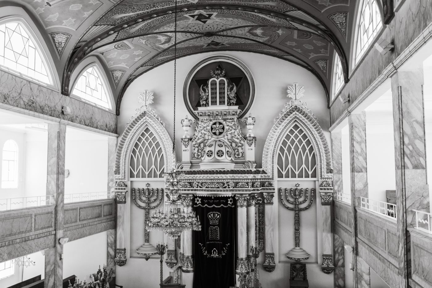 A synagogue sanctuary: the ark between two tall menorahs under a painted vault